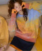 Person wearing a colorful sweater and gloves sitting on a couch.