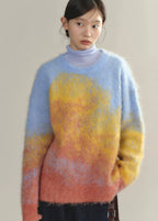 Person wearing a colorful sweater with a gradient from blue to yellow to pink.