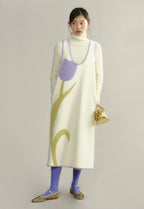 Woman wearing a long, light-colored dress with a floral pattern on a plain background