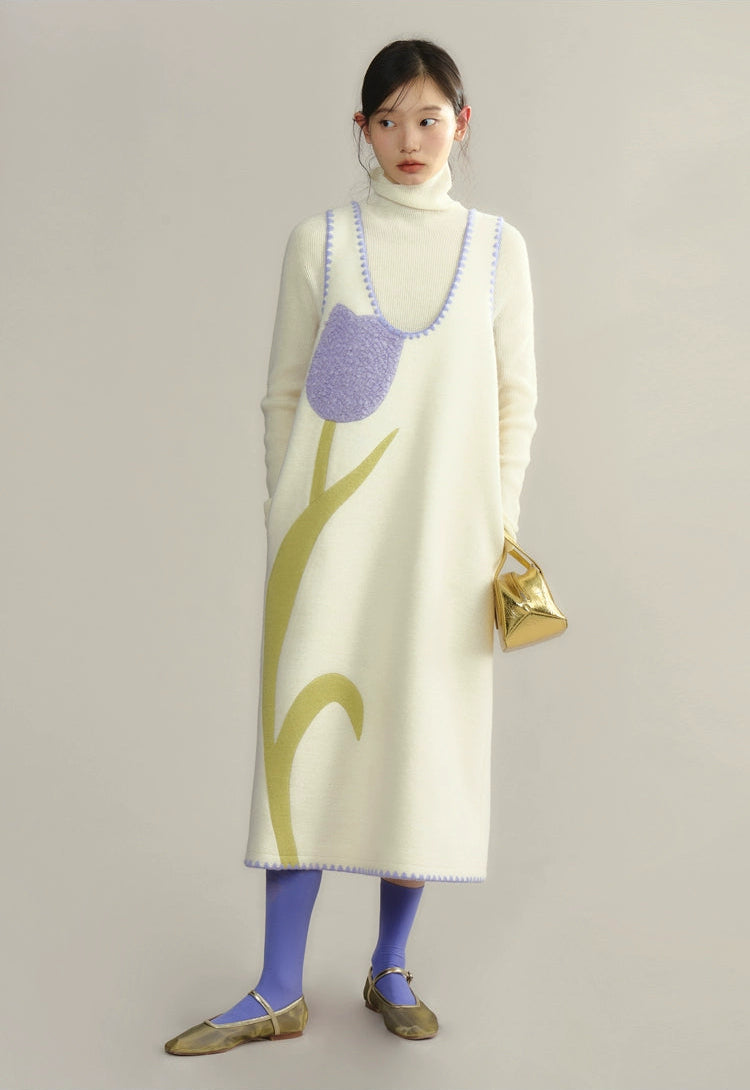 Woman wearing a long, light-colored dress with a floral pattern on a plain background