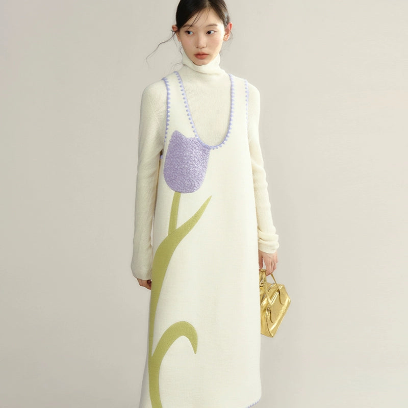 Woman wearing a long, cream-colored dress with a purple floral pattern on a plain background