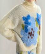 Fluffy sweater with blue floral design on a plain background