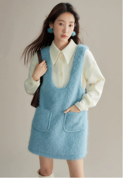 Woman wearing a light blue dress over a white shirt against a neutral background