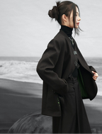 Person wearing a dark coat standing on a beach with a blurred background